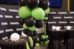 A bunch of black and green balloons are sitting on top of a table.  Balloon Columns for Deloitte