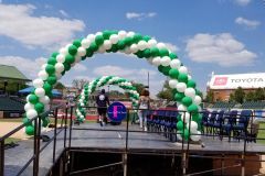 A green and white graduation balloon arch is sitting on top of a stage.