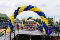A blue and yellow balloon arch is sitting on top of a graduation stage.