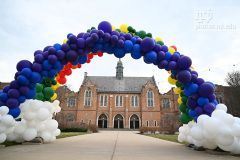 A large organic rainbow arch made of balloons is in front of a building at Notre Dame