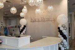 A reception area with balloons and chandeliers in a salon.