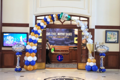 A room with balloons and a sign that says one thee notre dame for graduation.  Contains champagne bottle and glass.