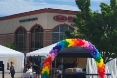 A rainbow colored balloon arch is in front of Martins Super Market.