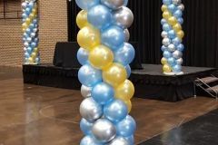 A room filled with blue , yellow , and silver balloons.