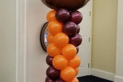 A column of orange and maroon balloons in a room.