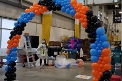 A woman is standing under a balloon arch in an Amazon warehouse.