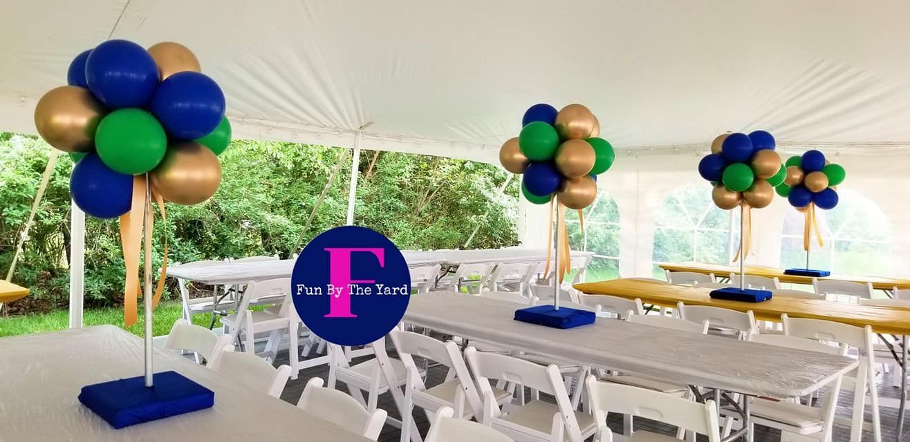 A tent with tables and chairs and balloons on top of them.