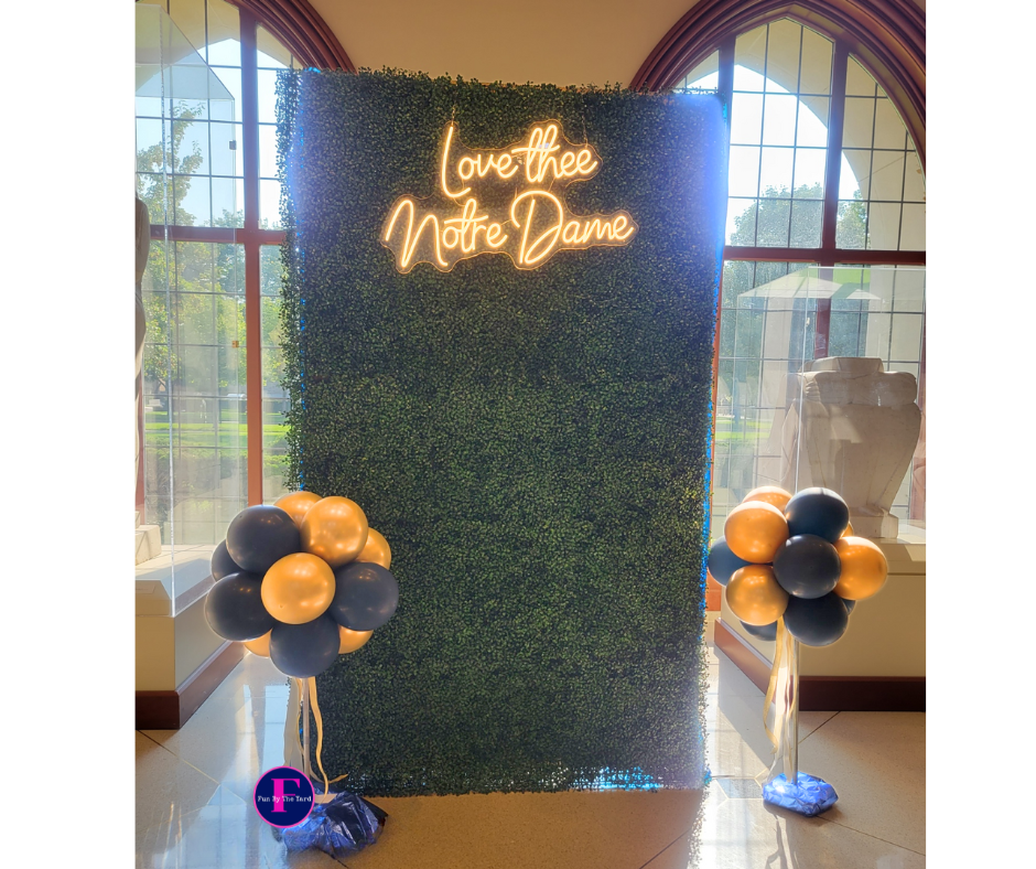 A neon sign that says `` love the notre dame '' is surrounded by balloons.