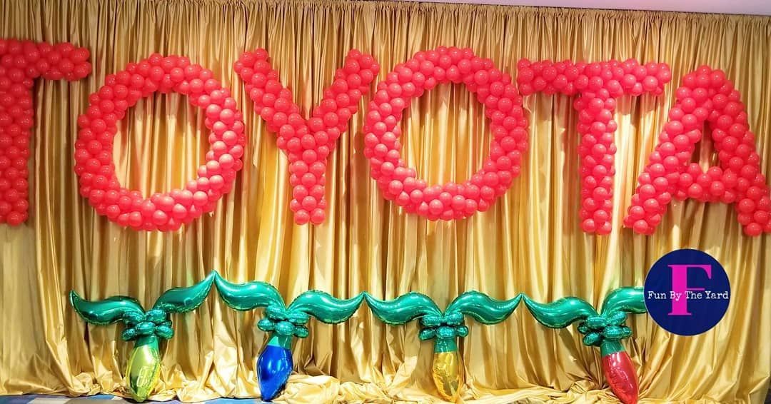 The word toyota is made out of red balloons on a gold curtain.