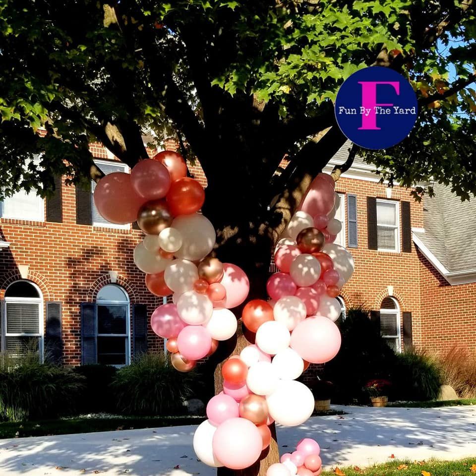 A tree is decorated with pink and white balloons and a sign that says party i 'm tard