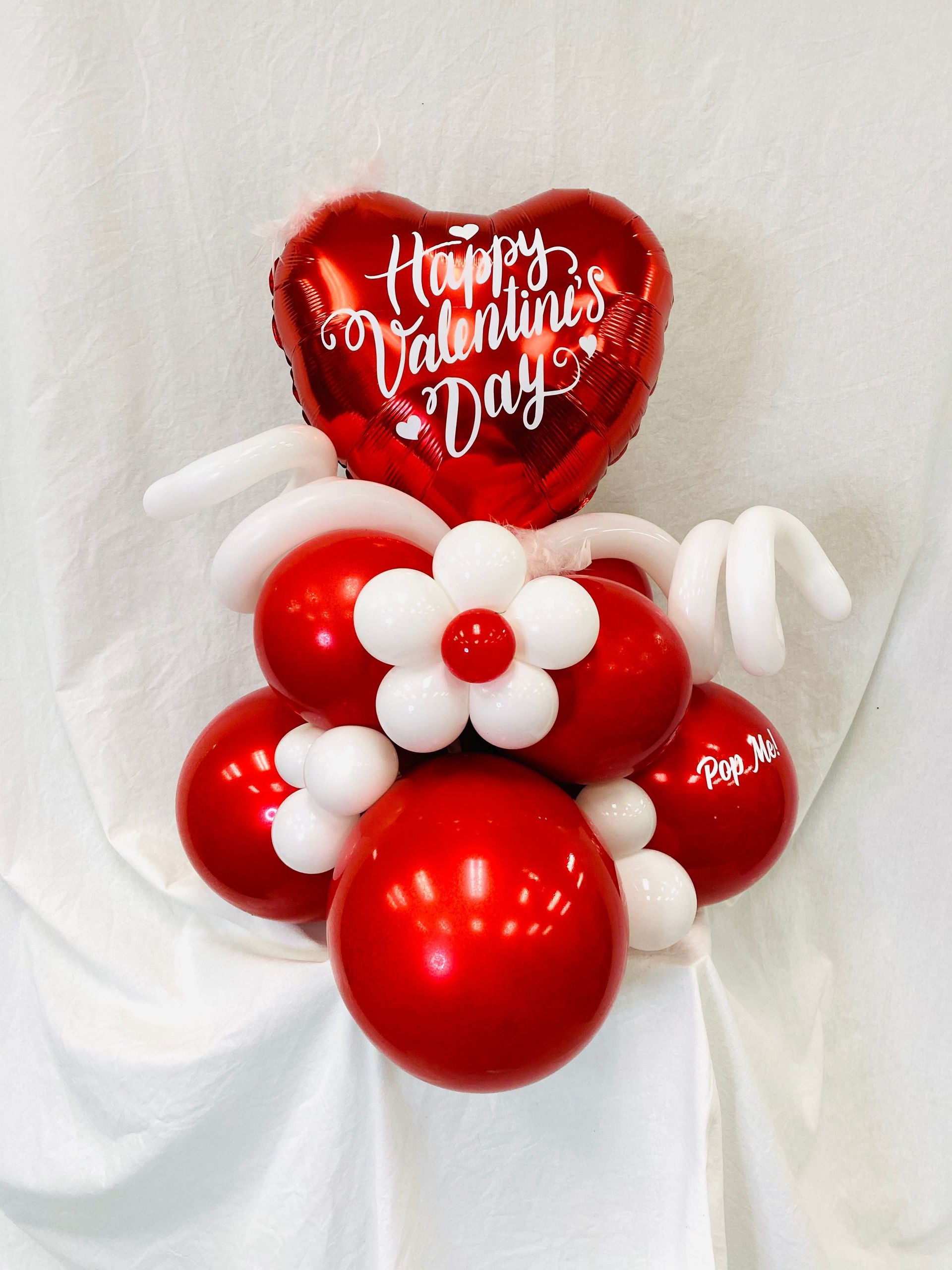 A happy valentine 's day balloon is surrounded by red and white balloons