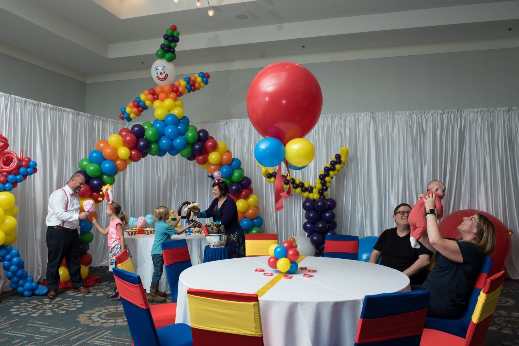 A group of people are sitting around a table decorated with balloons.
