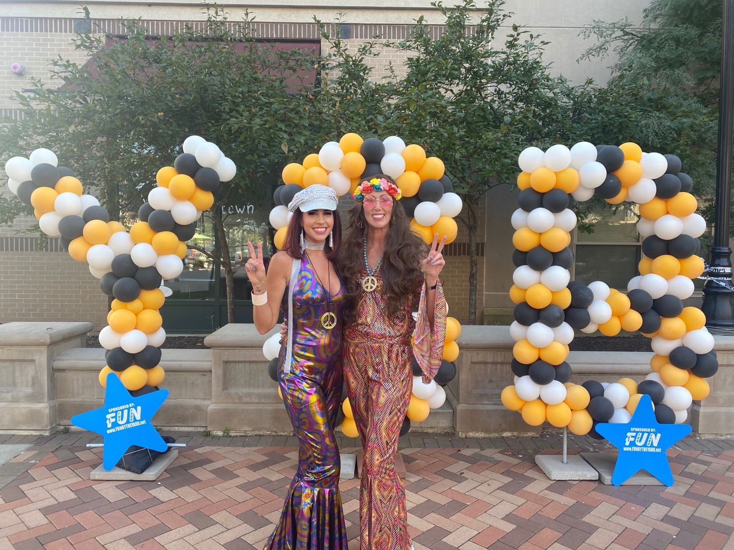 Two women are posing for a picture in front of balloons that spell YSB