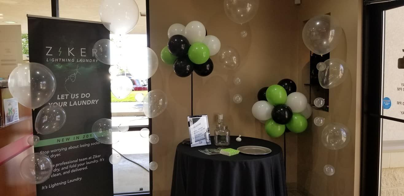 A room decorated with balloons and a table with a black tablecloth.