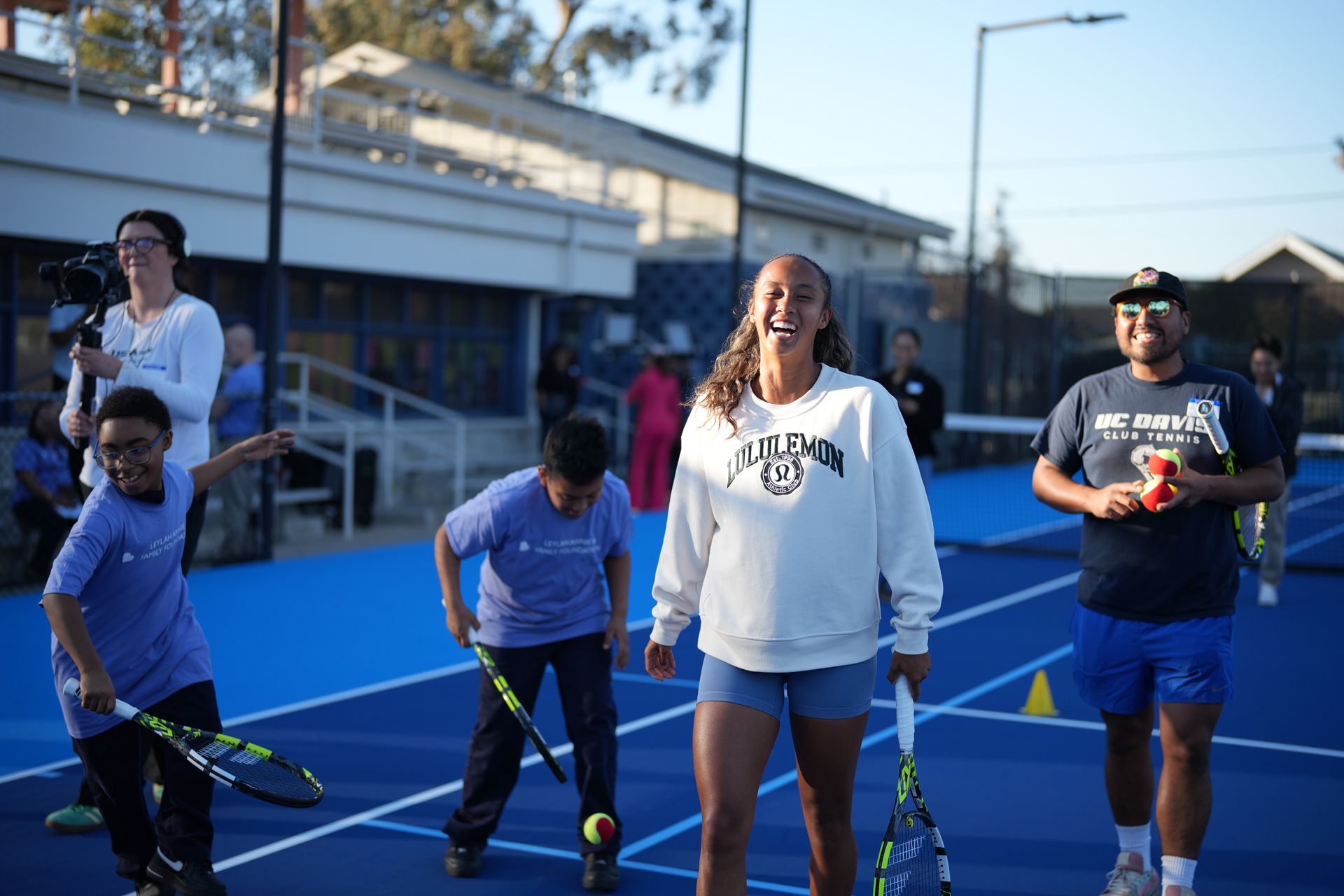 Leylah Fernandez laughing with Club members from on a tennis court 