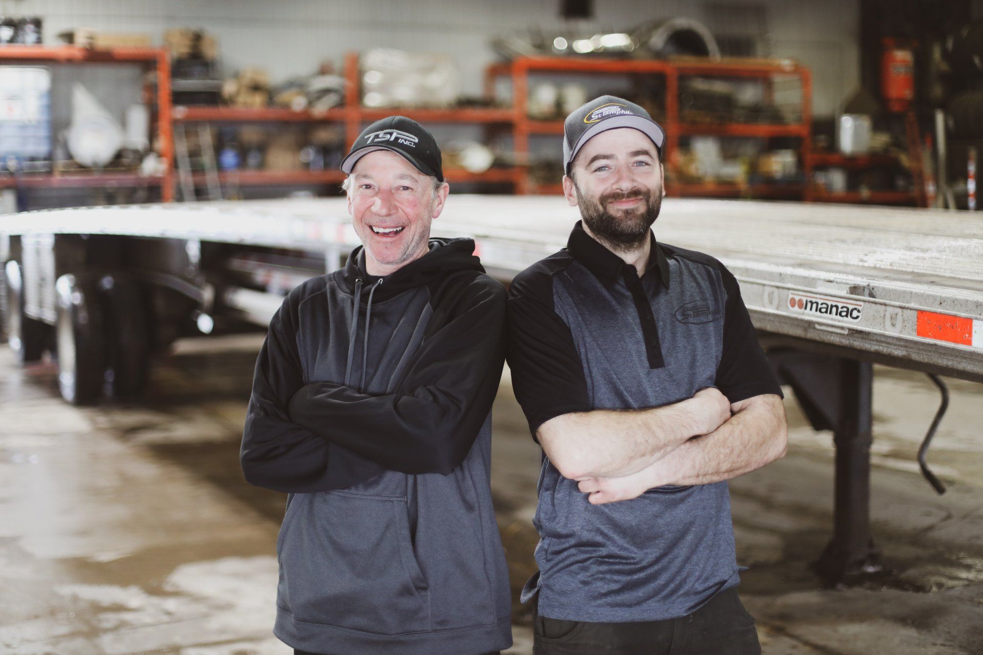 Deux hommes se tiennent côte à côte devant une remorque.