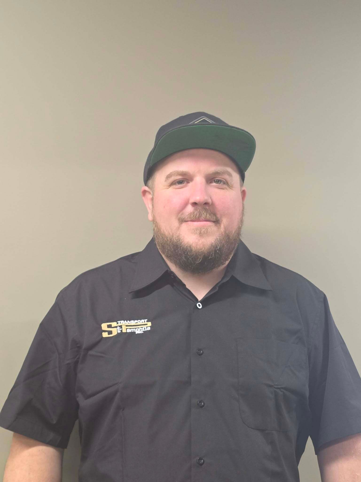 Un homme portant des lunettes et un chapeau sourit à la caméra.