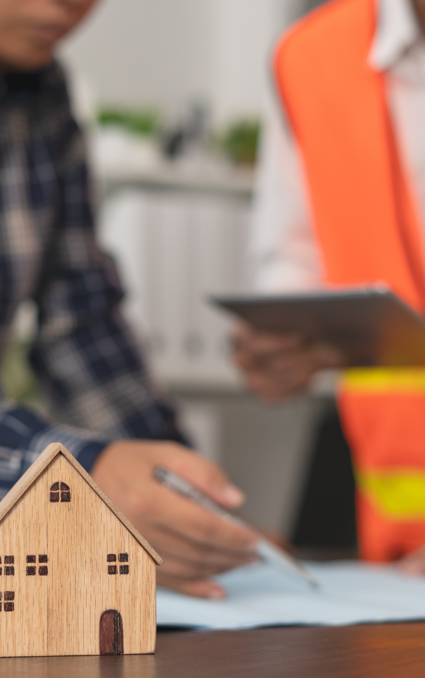 A man is writing on a piece of paper next to a small wooden house.