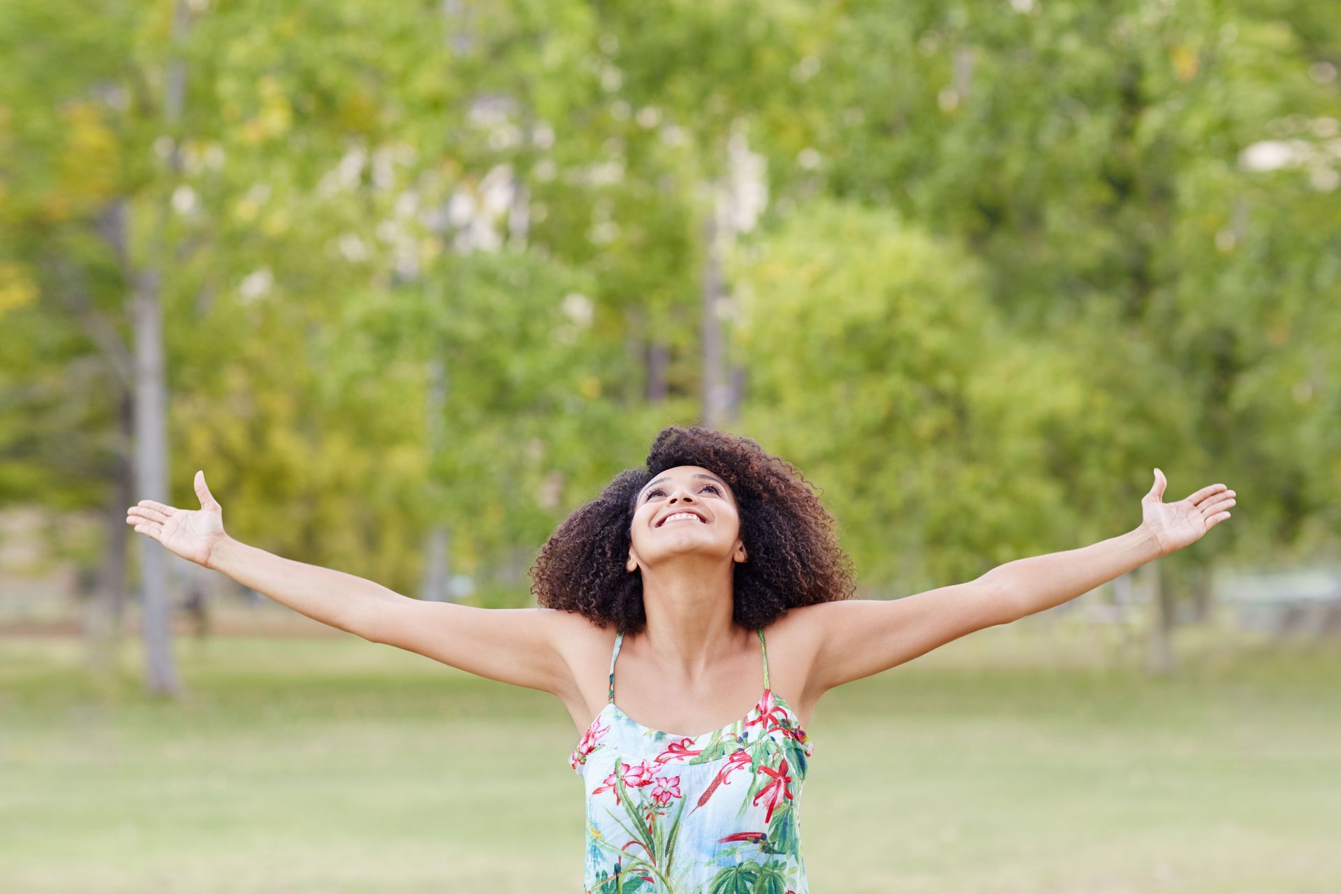 a woman is standing in a park with her arms outstretched .