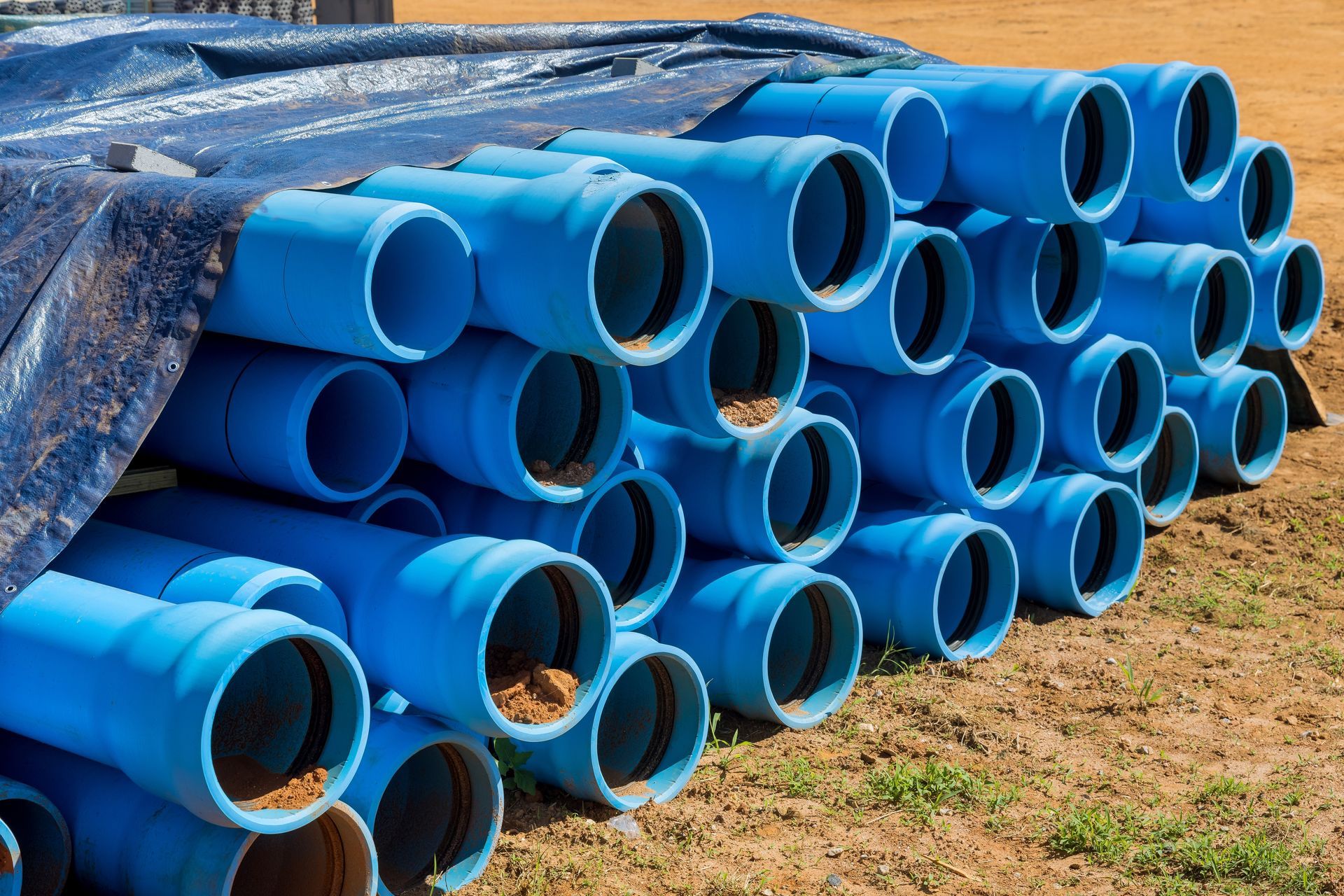 A bunch of blue pipes are stacked on top of each other on the ground.