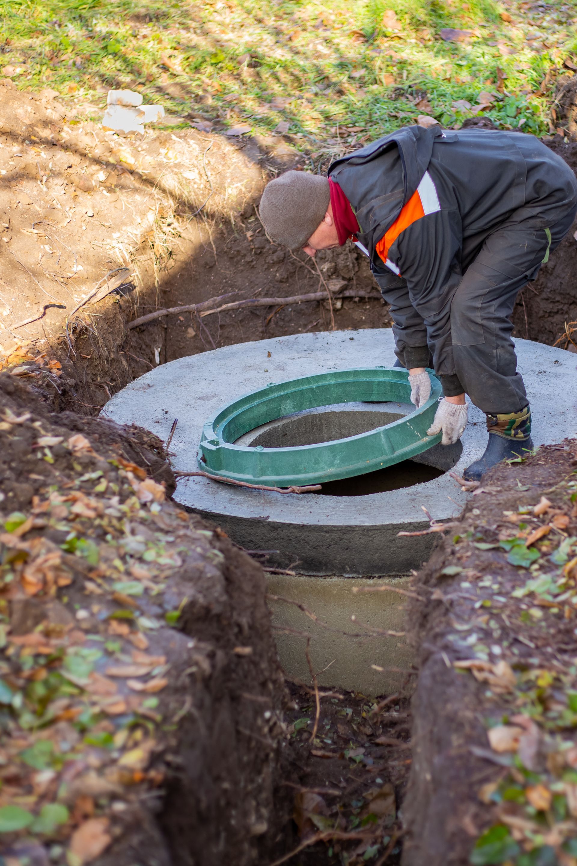 A man is working on a septic tank in a hole in the ground.