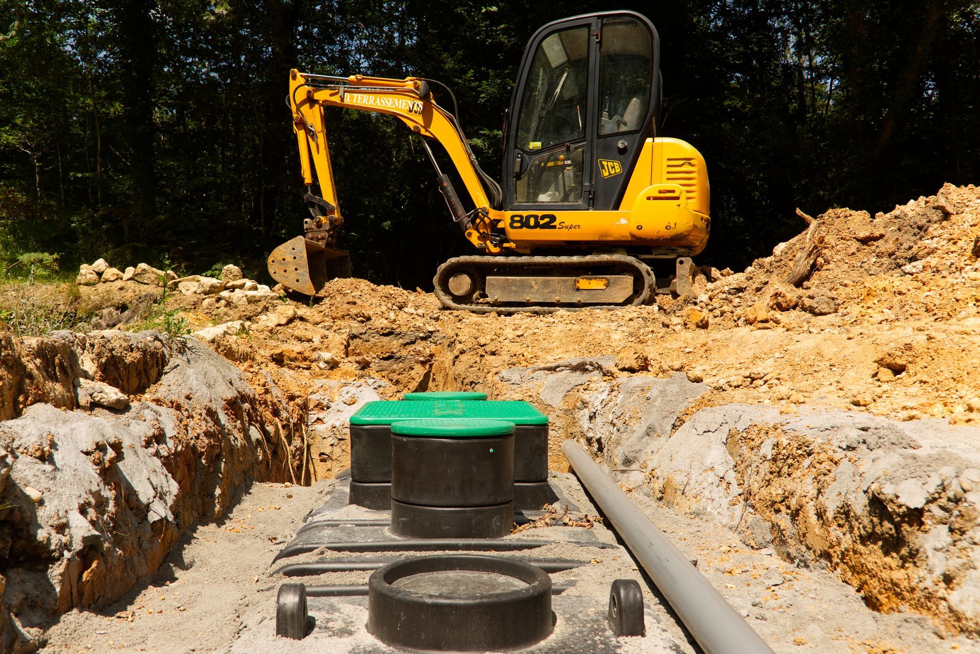 A yellow excavator is digging a hole in the dirt.