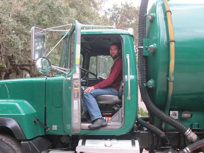 A man is sitting in the driver 's seat of a green truck