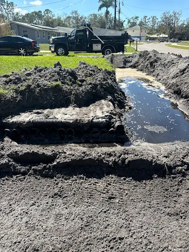 A dump truck is parked next to a large pile of dirt.