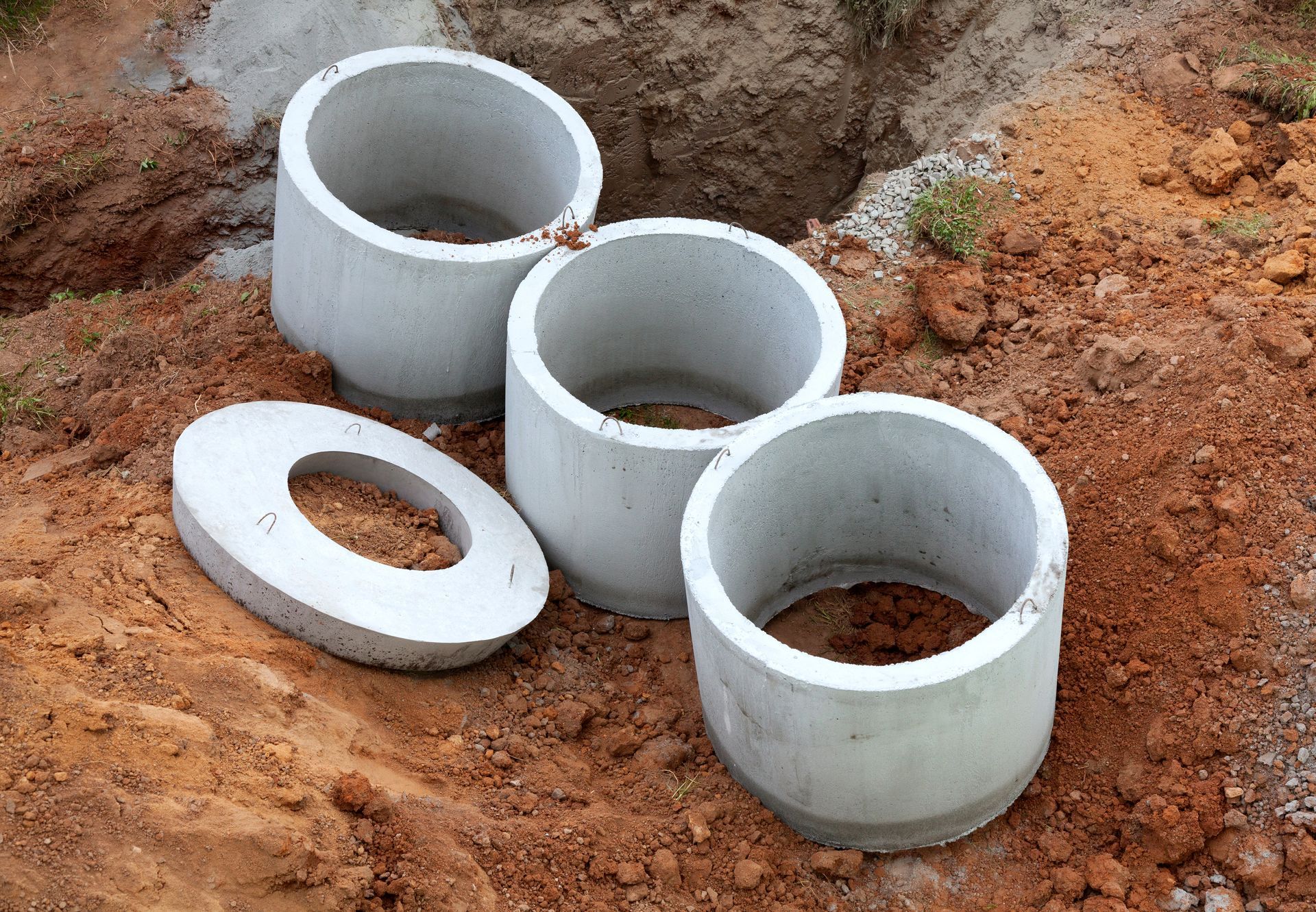 Three concrete rings are sitting on top of a pile of dirt.