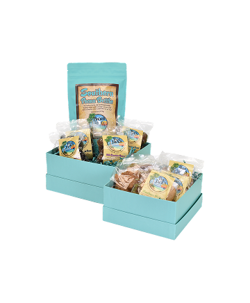 Two turquoise gift boxes filled with individually wrapped baked goods. A large bag sits in the back.