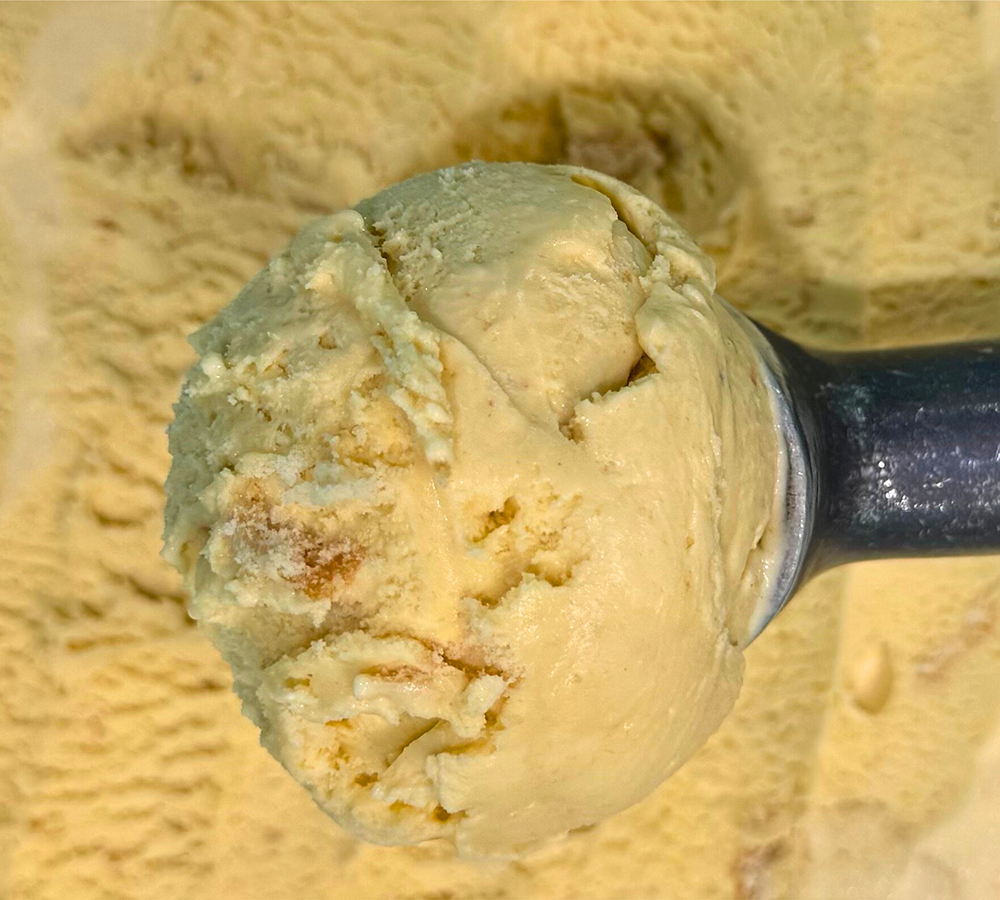 A close up of a scoop of vanilla ice cream on a plate.