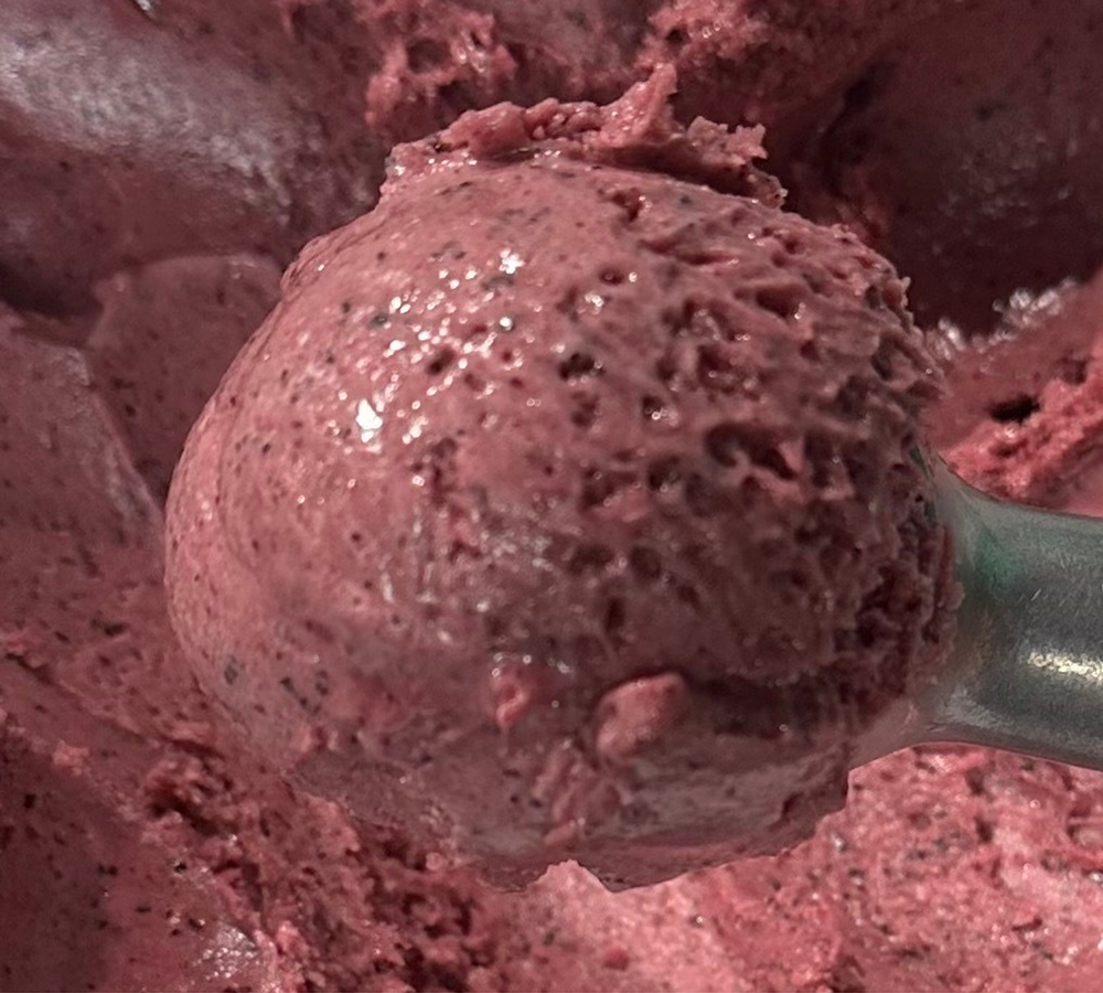 A person is holding a purple ice cream cone in their hand.
