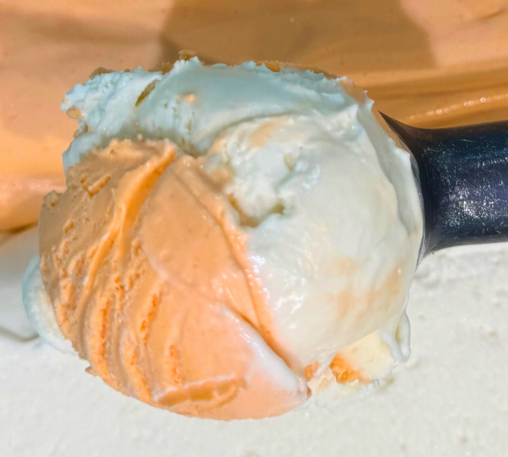 A close up of a scoop of blue ice cream on a spoon.