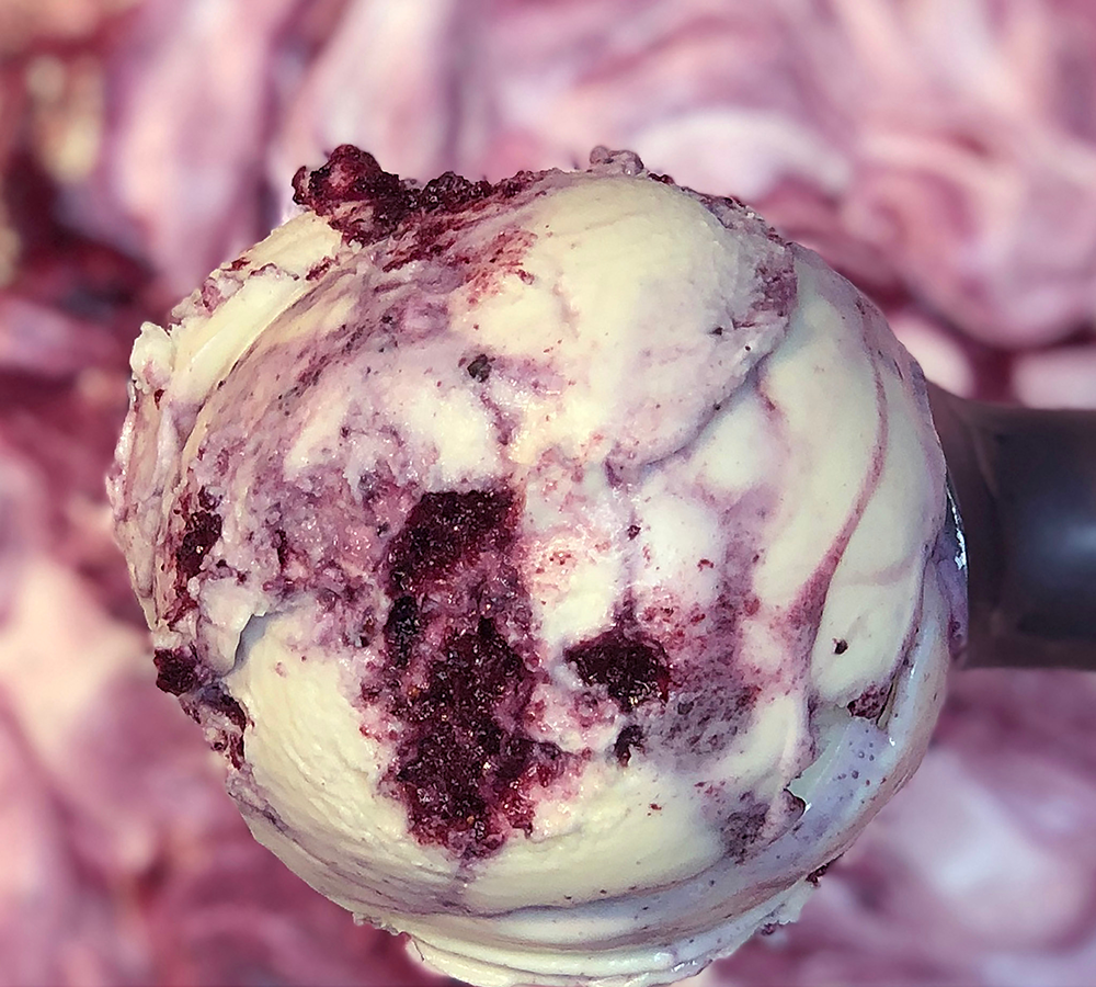 A close up of a scoop of ice cream with purple swirls