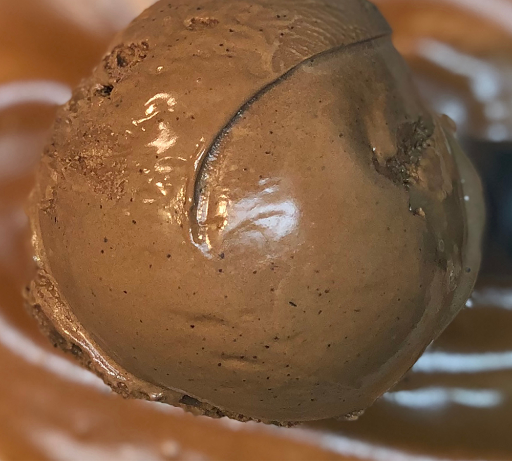 A close up of a scoop of ice cream on a white plate