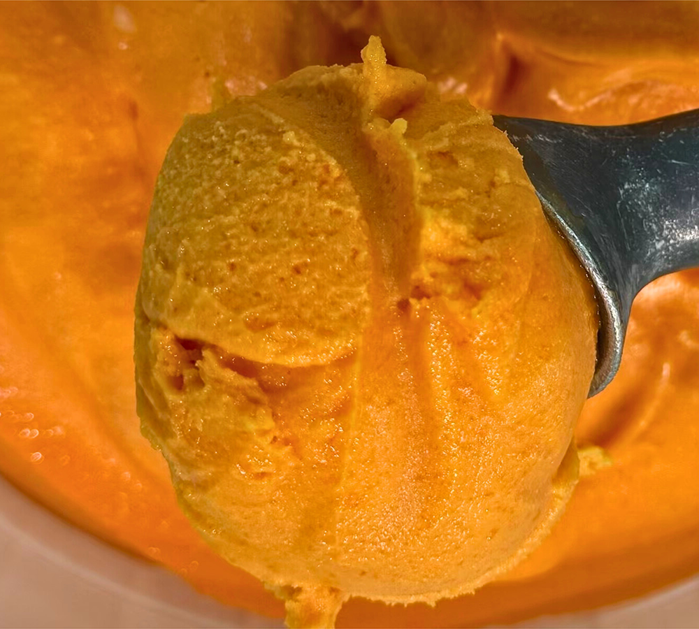 A close up of a scoop of ice cream on a white plate