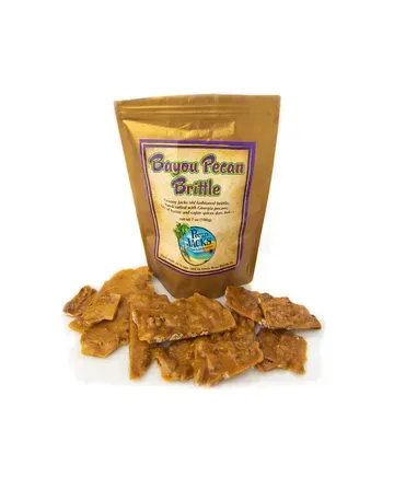 A bag of bayou pecan brittle is sitting next to a pile of brittle.