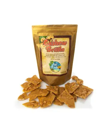 A bag of cashew brittle is sitting next to a pile of brittle.