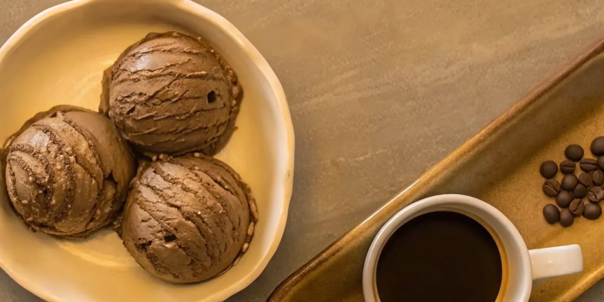 Three scoops of mocha ice cream in a bowl with a cup of coffee and coffee beans.