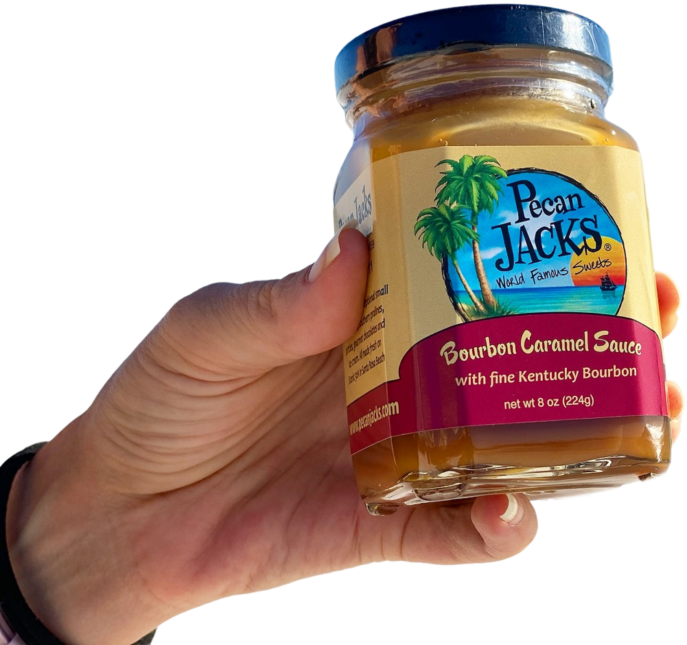 A person is holding a jar of pecan jacks bourbon caramel sauce