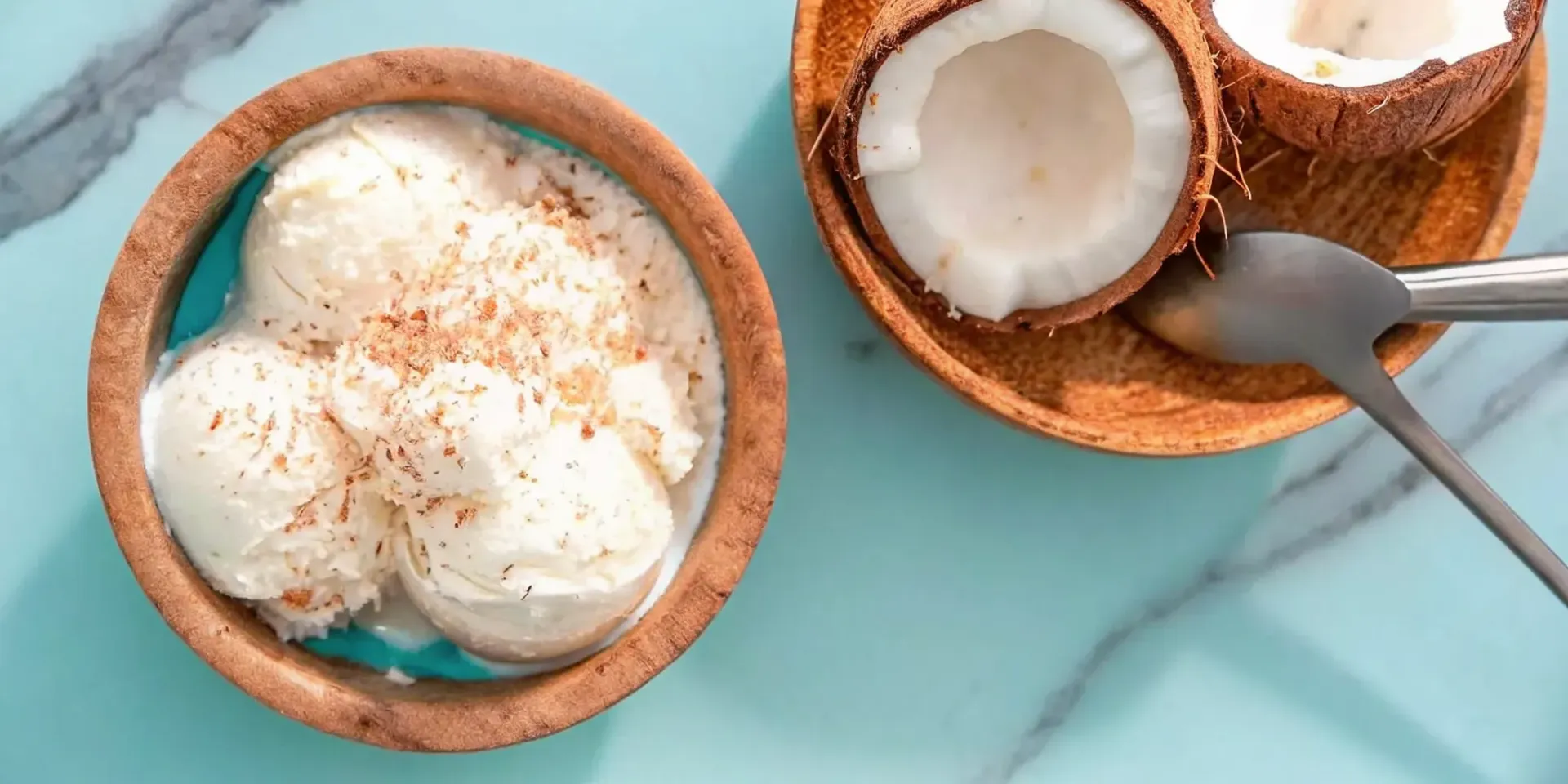 Scoops of creamy coconut ice cream in a bowl next to fresh coconut.