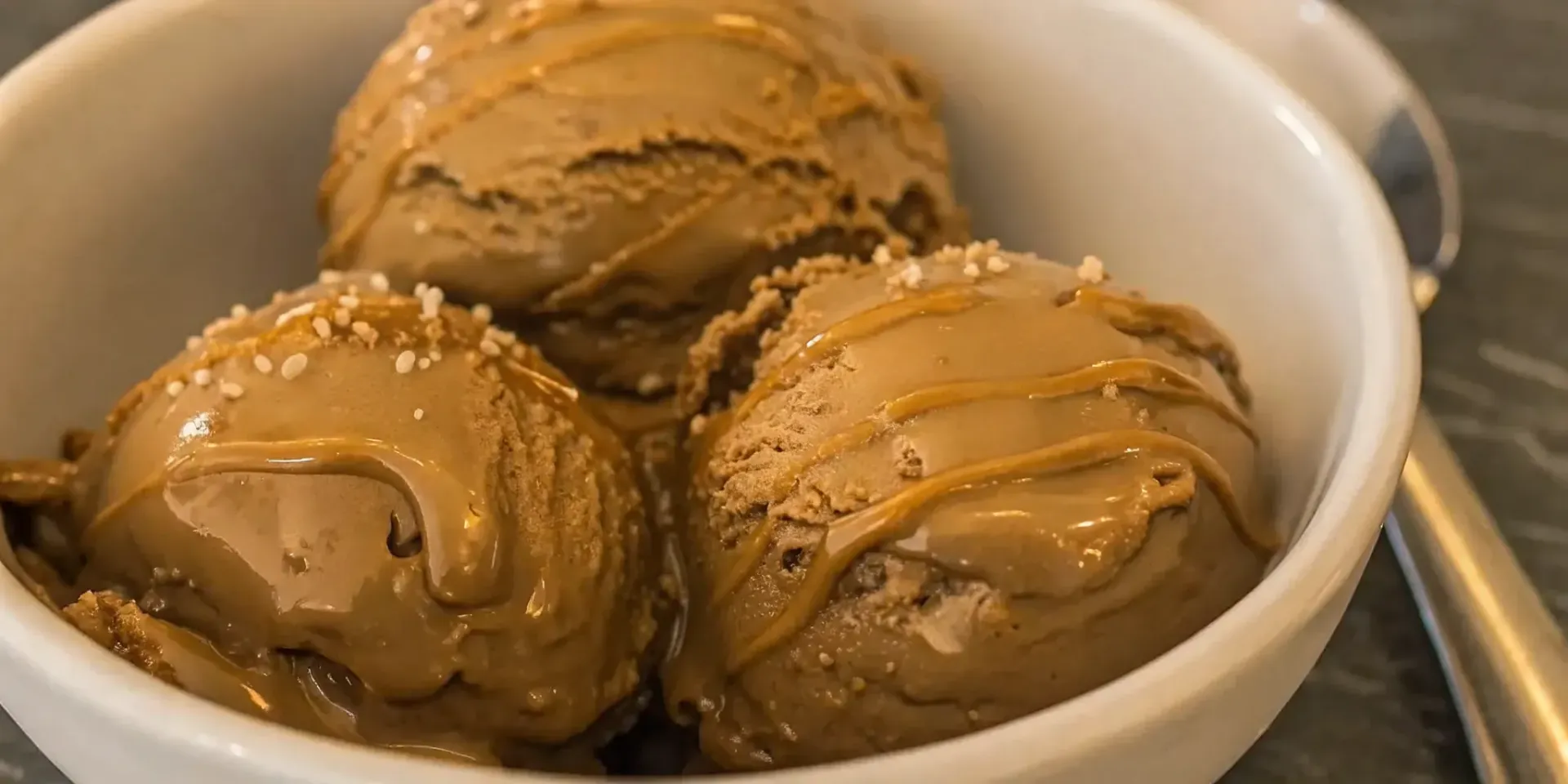 A bowl of Baileys salted caramel ice cream with a caramel drizzle and a sprinkle of sea salt.