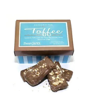 A box of toffee with nuts on top of it.
