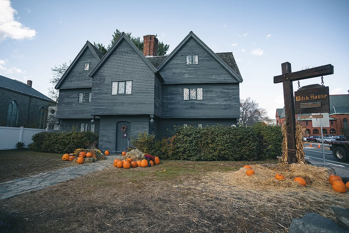 Dark wooden house with pumpkins and a sign in front, likely in Salem.