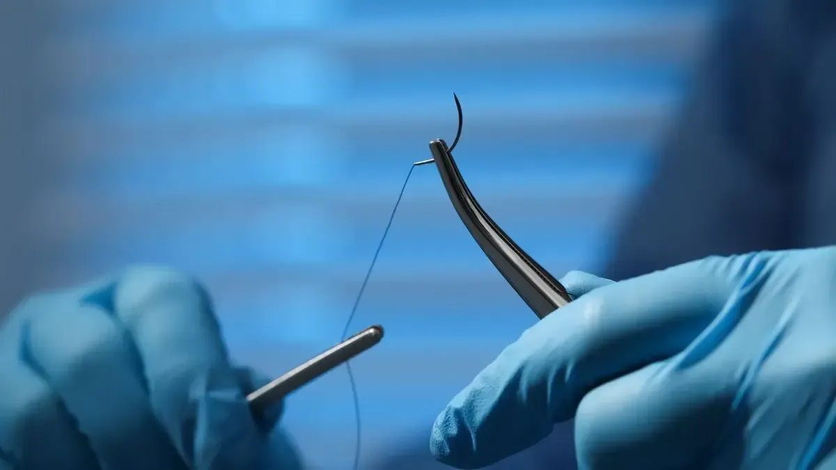 A close up of a person holding a pair of scissors and a needle.