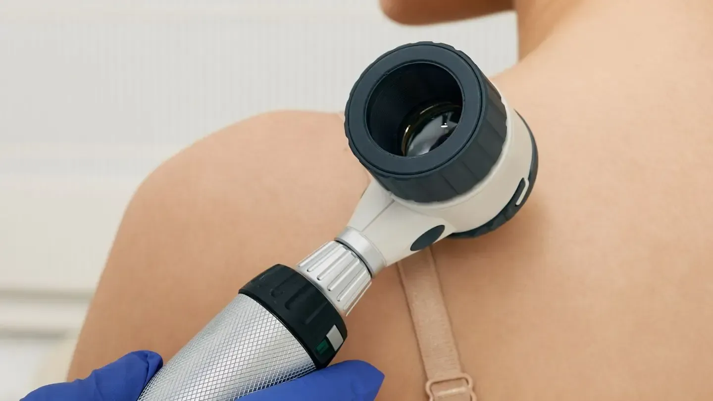 A doctor is examining a woman 's back with a light.