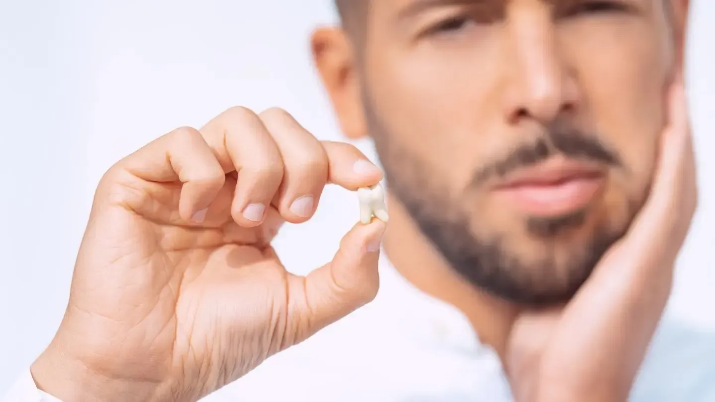 A man is holding a tooth in his hand and has a toothache.