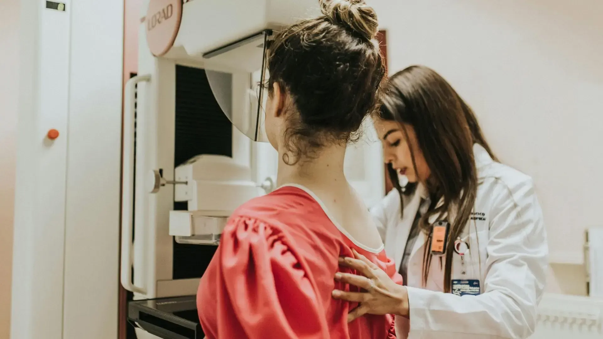 Woman getting a mammogram, assisted by a healthcare provider in a medical setting.