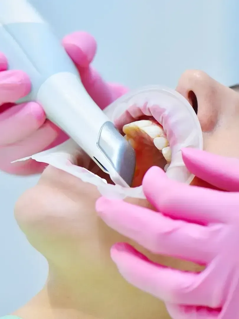 A person is holding a toothbrush in front of an x-ray of a person 's teeth.