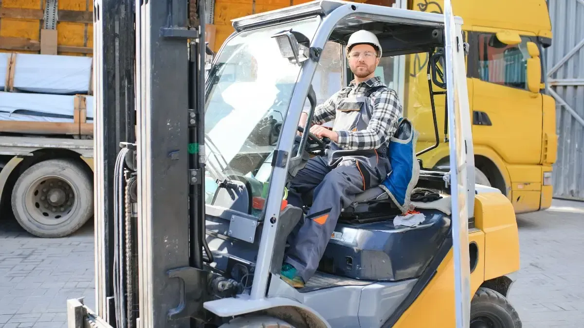 Man in hard hat operating a yellow forklift, loading a truck.